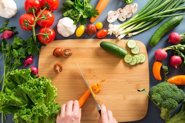 Top view of woman cooking healthy food: cutting vegetable ingredients..  Hands in the image. Horizontal; Shutterstock ID 605725148